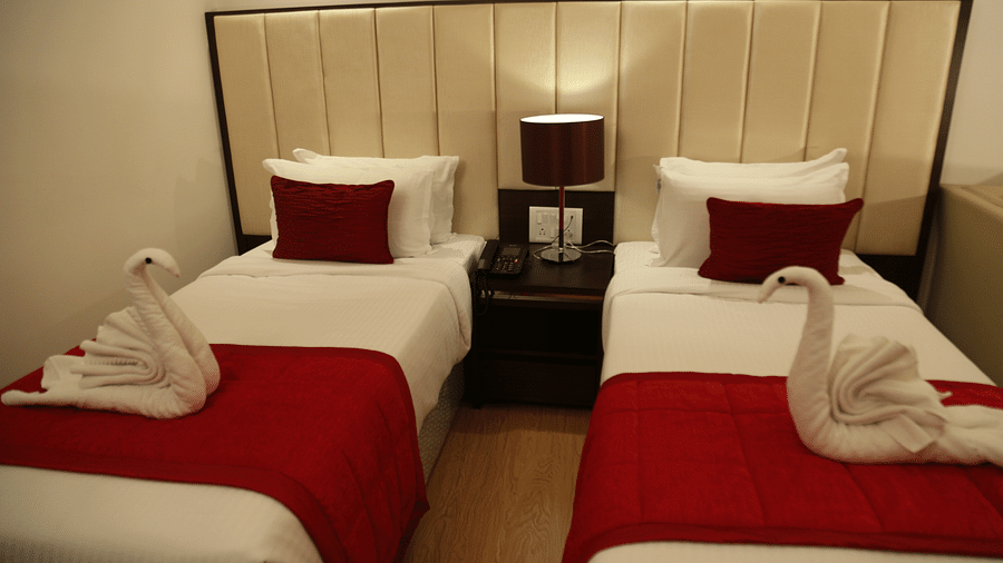 A hotel room with twin beds with red accents and towel swans on top - TGI Grand Fortuna, Hosur