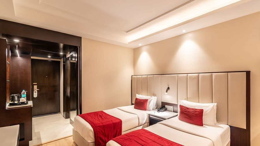 Superior Room with two beds featuring patterned bedding, a desk area, and lighting- TGI Grand Fortuna, Krishnagiri Main Road, Hosur
