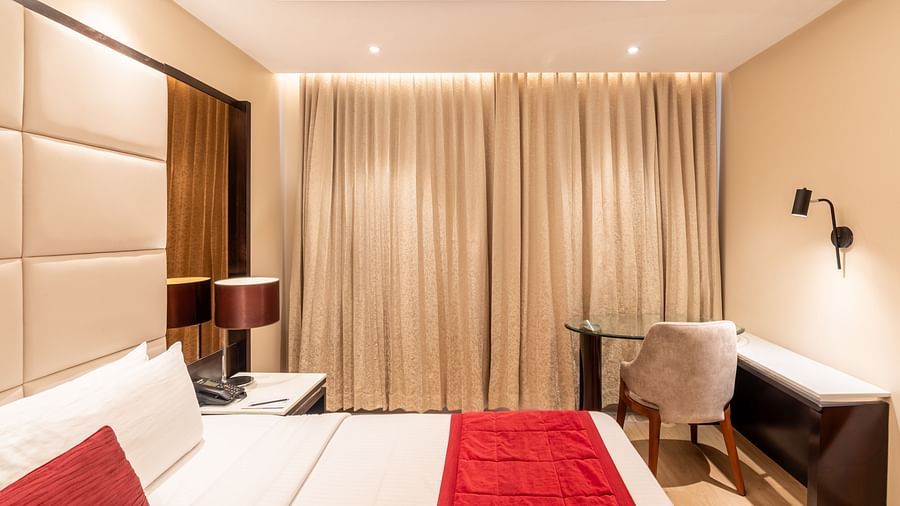 Fortuna suite's room featuring a large bed, curtains, and work desk- TGI Grand Fortuna, Krishnagiri Main Road, Hosur