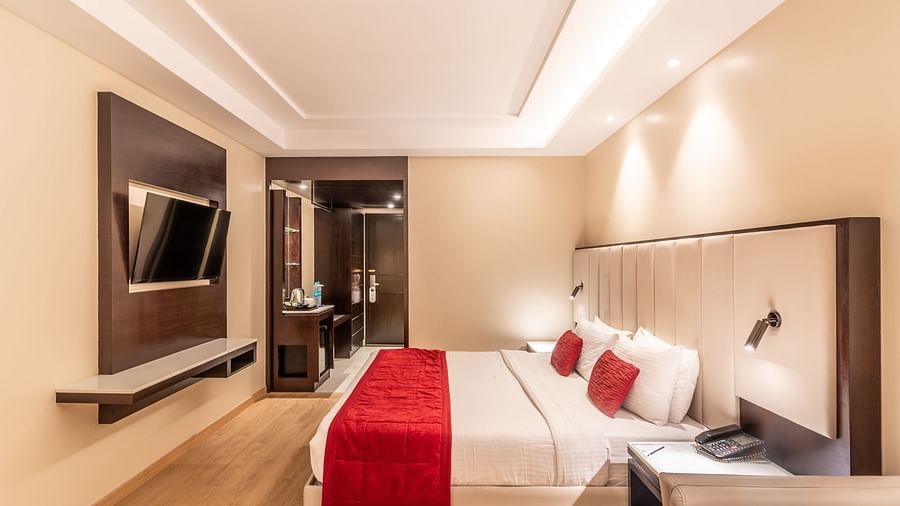 Bedroom with mounted TV, bedside lighting, and seating area- TGI Grand Fortuna, Krishnagiri Main Road, Hosur