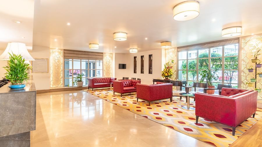 Elegant hotel lobby with modern furniture, red armchairs, and large window- TGI Grand Fortuna, Krishnagiri Main Road, Hosur