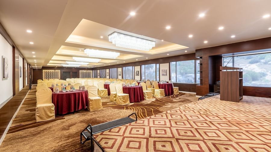 Versatile banquet space with podium and large windows, set for a business meeting or seminar