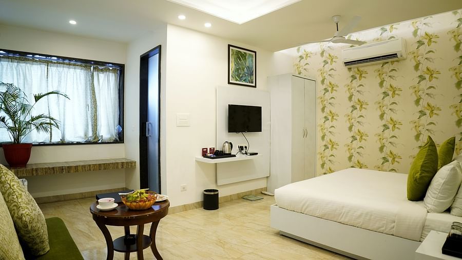 A serene bedroom setup with a large window and a white and green colour scheme - TGI Insignia, Bhopal