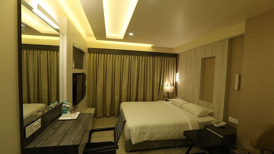 Premium Room featuring a king size bed, desk with a mirror, chair, and ambient lighting, showcasing the room's layout and decor - TGI SPS Grand, Coimbatore