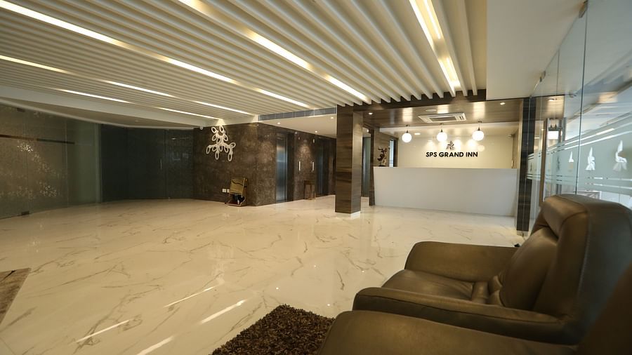 A spacious, well-lit lobby area with modern ceiling lights, light-coloured flooring, and comfortable lounge seating - TGI SPS Grand, Coimbatore