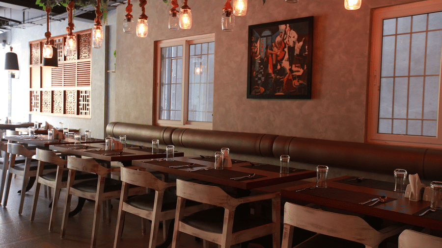The interior of the main dining room featuring long wooden tables, dark placemats, and warm hanging lights at The Bull Boutique Hotel.