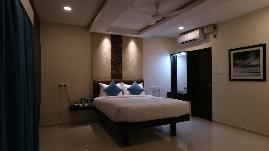 A well-appointed guest room with a queen bed, ambient recessed lighting, and a framed black-and-white photo on the wall at The Bull Boutique Hotel.