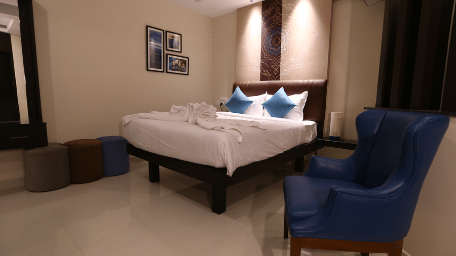 A cosy corner of a guest room featuring a high-back blue armchair and colourful round ottomans at The Bull Boutique Hotel.