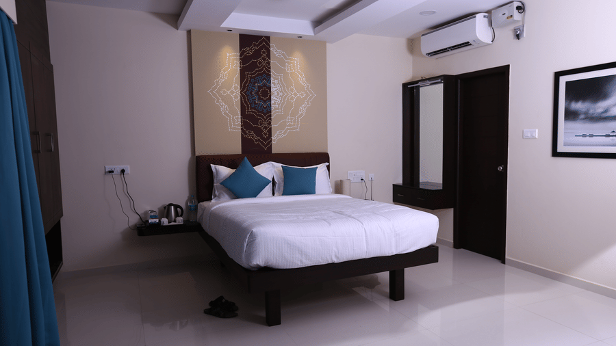 A bright hotel room view showing the air-conditioning unit, wall-mounted desk, and decorative headboard panel at The Bull Boutique Hotel.