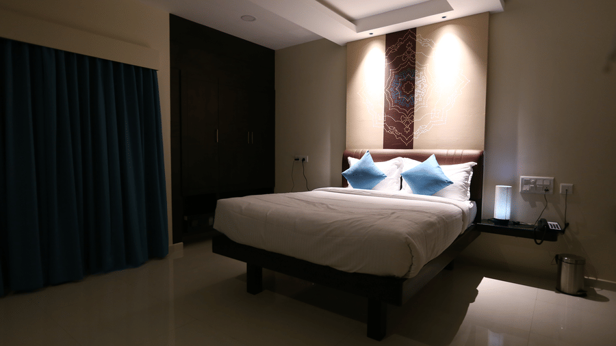 A minimalist bedroom scene captured with soft evening lighting and floor-to-ceiling teal drapes at The Bull Boutique Hotel.