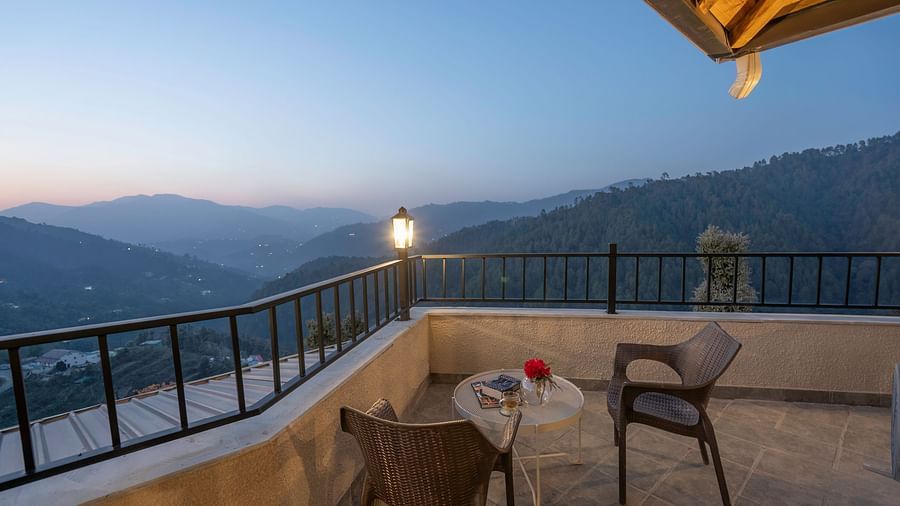 Balcony with a table and chairs overlooking the mountains, featuring a metal railing with a light at the corner at The Chamomile Estate.