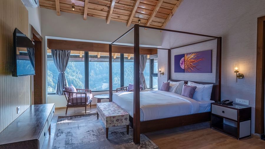 Bedroom with a four-poster bed, bedside table, and large windows offering a view, and a desk positioned below a wall-mounted television at The Chamomile Estate.