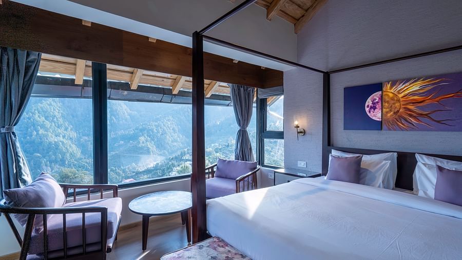 Bedroom with a four-poster bed and chairs facing a window view, with curtains pulled to the sides at The Chamomile Estate.