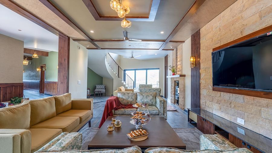 View of a stylish living room, featuring furniture arranged around the table and a wall-mounted television at The Chamomile Estate.