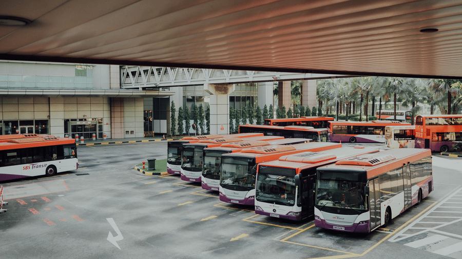 busses parked next to each other in a bus depot as seen from a distance
