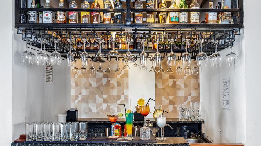 A well-stocked bar with various liquor bottles on shelves and wine glasses hanging upside down | The Citi Residenci Hotel Banskopa