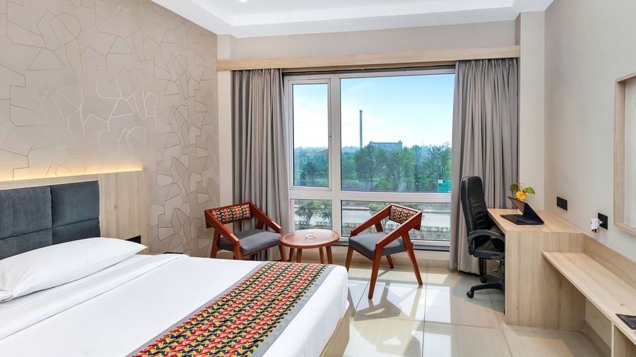 A bright hotel room with a bed, seating area, and work desk by a window | The Citi Residenci Hotel Banskopa