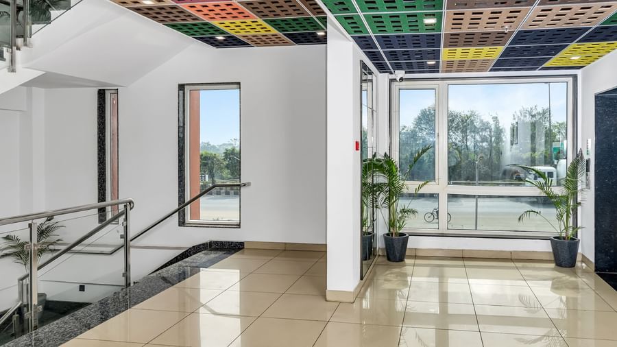 An interior space with a colourful patterned ceiling, large windows, and potted plants | The Citi Residenci Hotel Banskopa