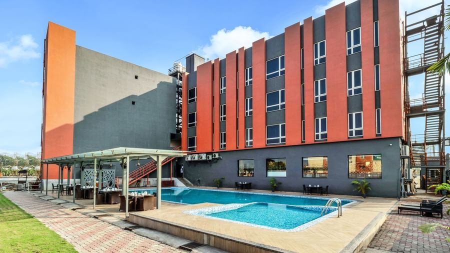 A modern hotel with a swimming pool and outdoor seating area under a partly cloudy sky | The Citi Residenci Hotel Banskopa