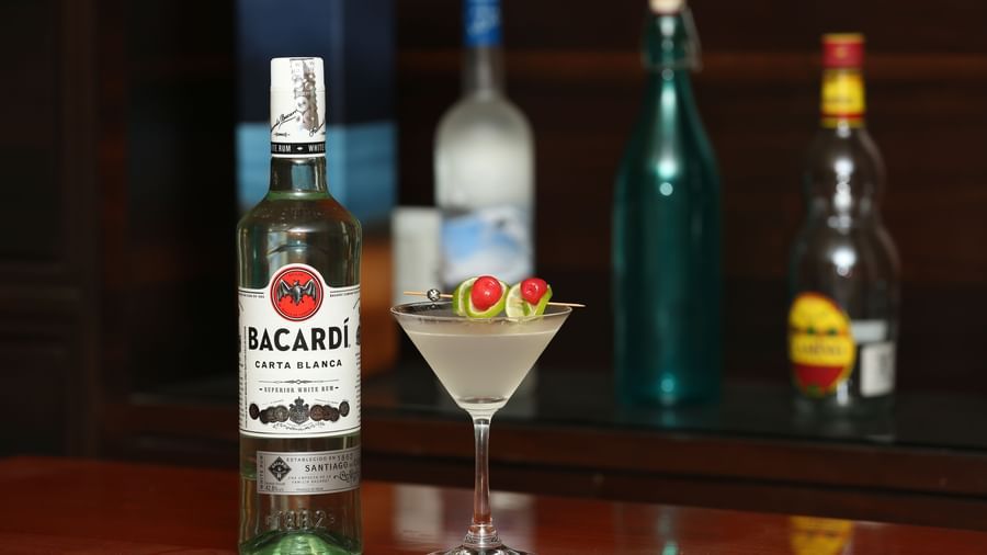 A bottle of Bacardi and a cocktail glass on a bar counter at The Citi Residenci Hotel, Durgapur.