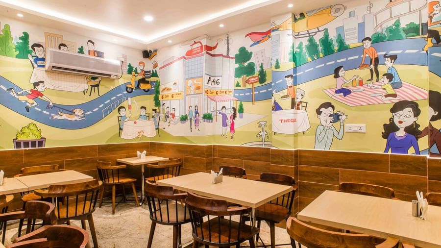A spacious dining area with colourful wall art and wooden furniture at The Citi Residenci Hotel, Durgapur.