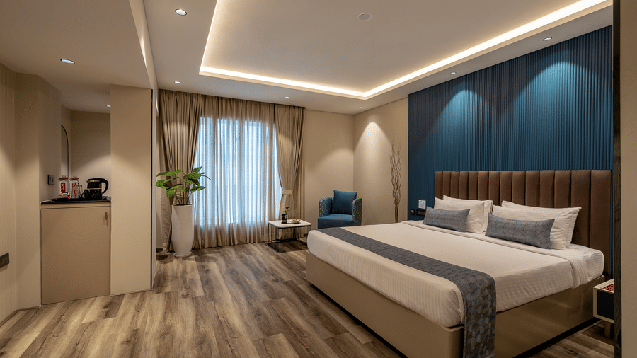 Club Room at The Citrine, Bangalore, with a king bed, brown headboard, blue fluted accent wall, tea station, and sheer curtains over a window.