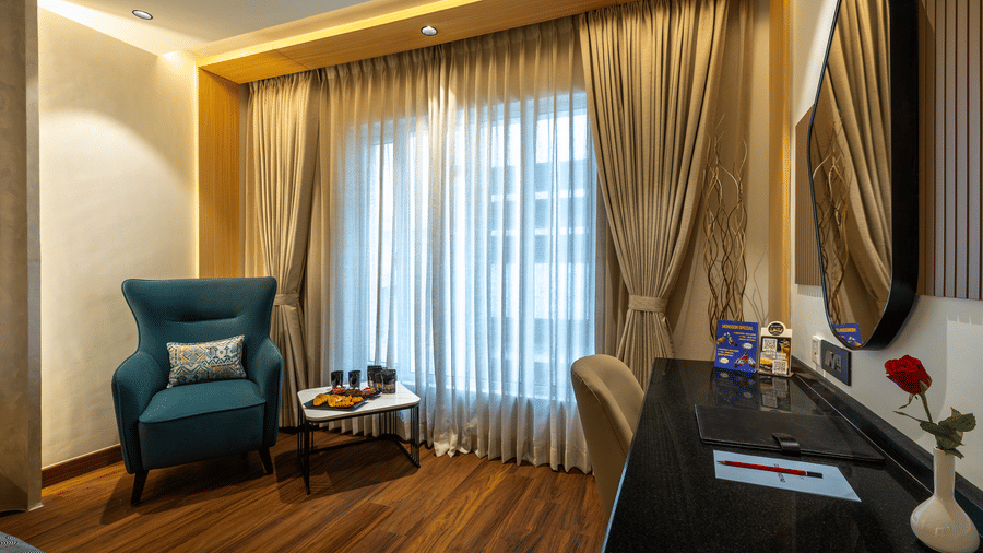 Executive King Room at The Citrine, Bangalore, with a single bed, dark green headboard, breakfast tray, armchair, and floor-to-ceiling sheer curtains.