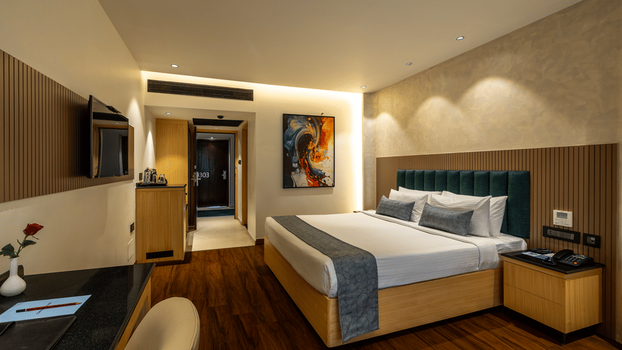Executive King Room at The Citrine, Bangalore with a king bed, green tufted headboard, a wall-mounted TV, a work desk, and an abstract framed art.