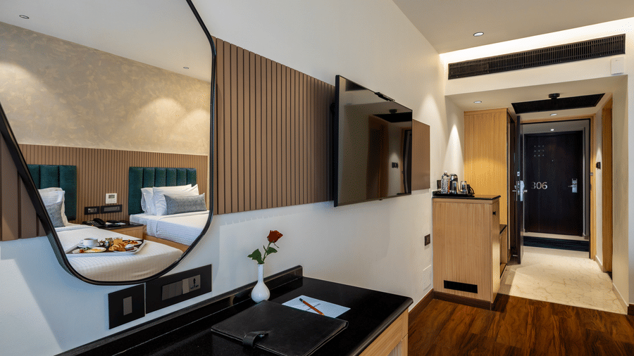 A view from a dark wooden desk looking towards the room entrance, and twin beds at The Citrine, Bangalore.