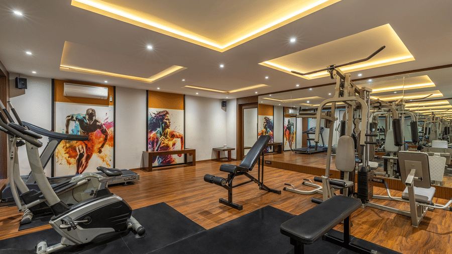 Well-lit fitness centre featuring treadmills, weight benches, and multi-gym equipment with wood flooring, and recessed ceiling lights at The Citrine, Bangalore.