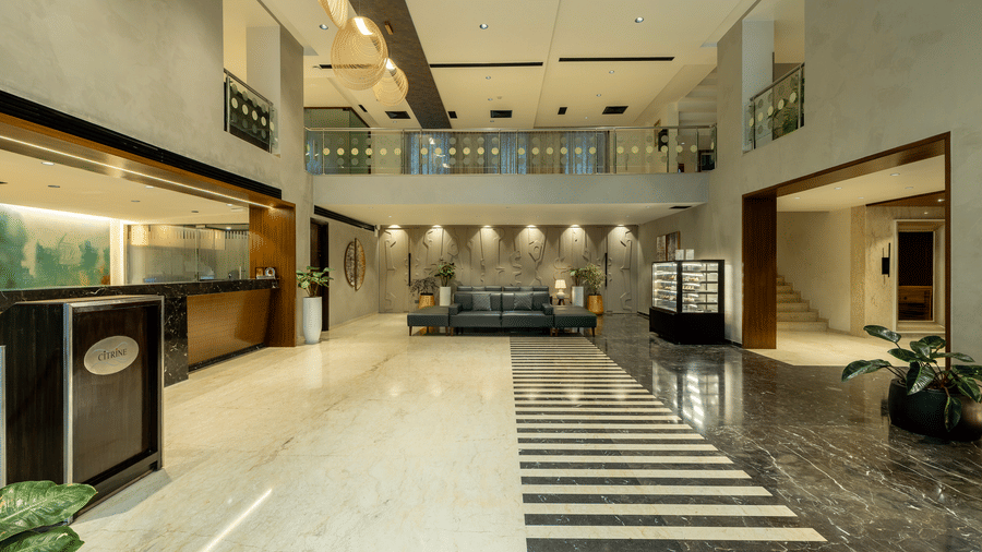Lobby at The Citrine, Bangalore, with double-height ceiling, pendant lights, reception desk, marble flooring, and a black-and-white striped inlay.