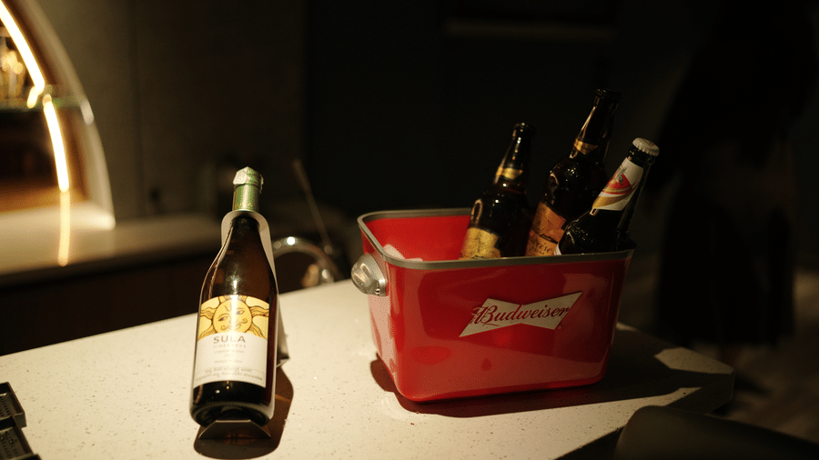 Several bottles placed in a trunk and a bottle placed adjacently on a table.