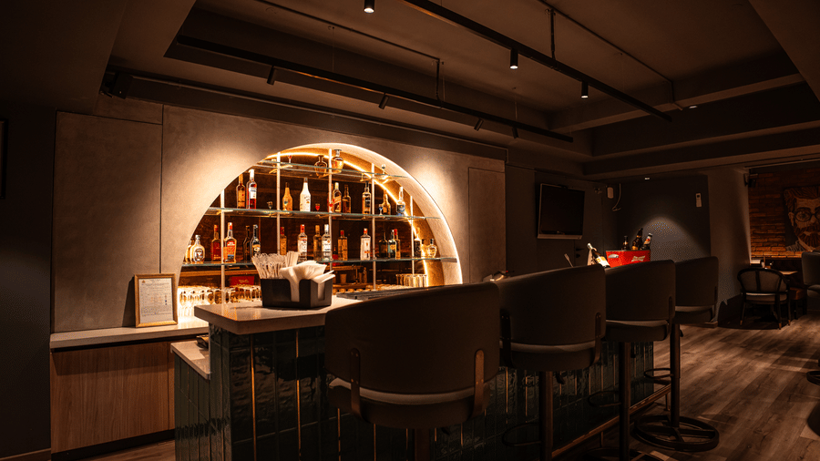 Elegant bar counter setup with backlit shelves and premium ambiance at Trino Bar
