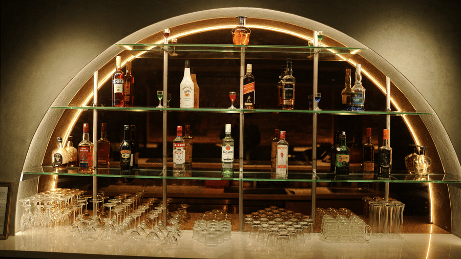 Citrine Hotel | A bar counter with bottles placed on shelves.