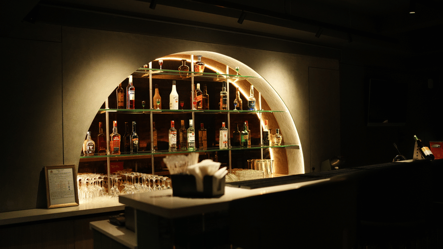 Citrine Hotel | A bar counter with bottles placed on shelves.