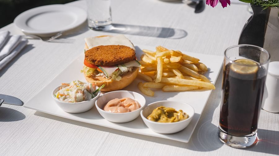 image of a burger along with french fries served with several dips