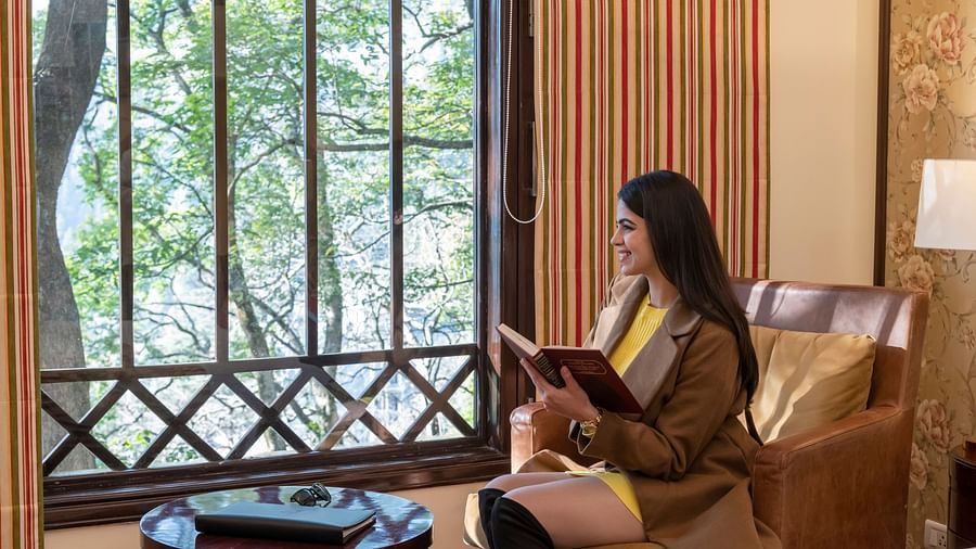 image of a woman reading a book besides the window of the duplex family suite