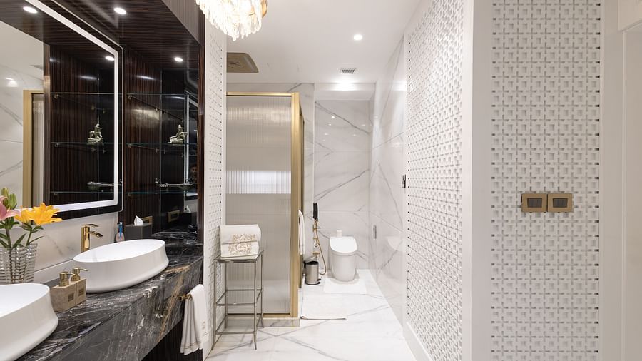 Claridges Suite washroom at The Claridges New Delhi, showcasing sleek sinks, a wall-mounted mirror, and elegant lighting