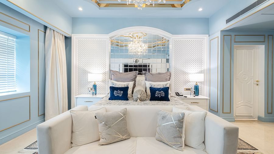 Claridges Suite at The Claridges New Delhi, highlighting the front view of a plush bed flanked by bedside lamps and illuminated by a chandelier overhead