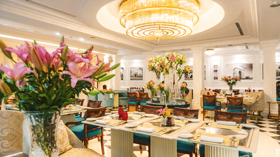A beautifully designed restaurant featuring a grand chandelier, floral arrangements, and stylish seating