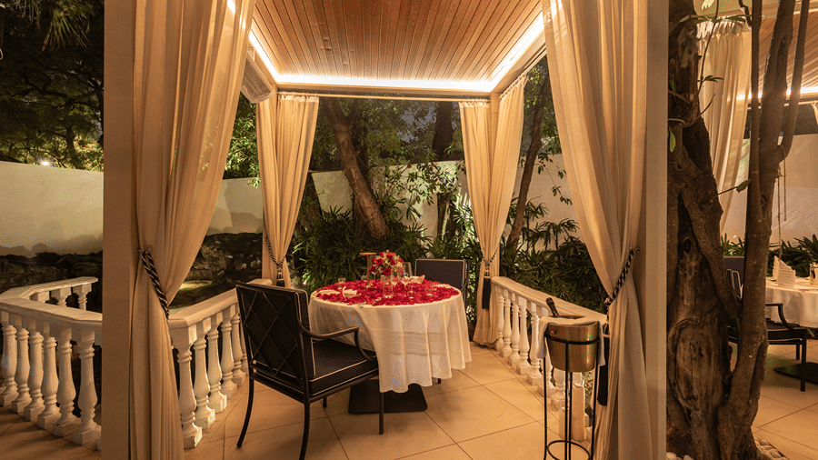 A charming gazebo-style setup with ambient lighting, elegant drapery, and greenery around