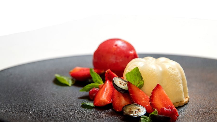 Image featuring an exquisite plated dessert with berries, white chocolate mousse, and a red glaze