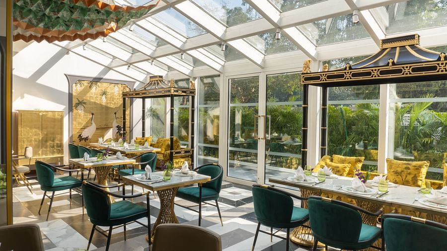 Image featuring the Jade dining section at The Claridges New Delhi, offering elegant seating arrangements beneath a glass rooftop with a direct view of the sky