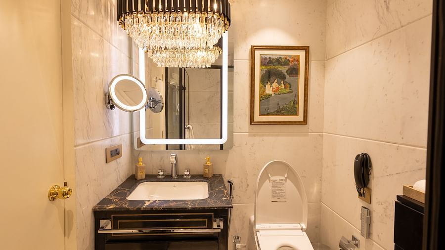 Luxury Suite washroom at The Claridges New Delhi, featuring a stylish sink, wall-mounted mirror, and a chandelier