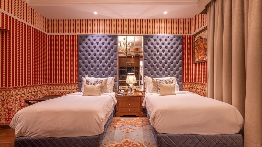 Front view of the Luxury Twin Bed Room with Balcony at The Claridges New Delhi, featuring two separate beds with a bedside lamp placed between them