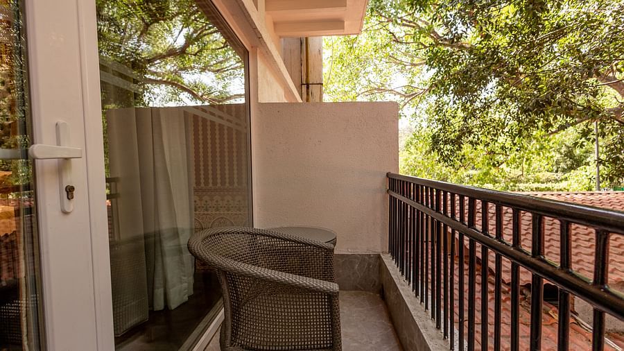 Balcony of the Luxury Twin Bed Room with Balcony at The Claridges New Delhi, featuring a comfortable chair and a glass door