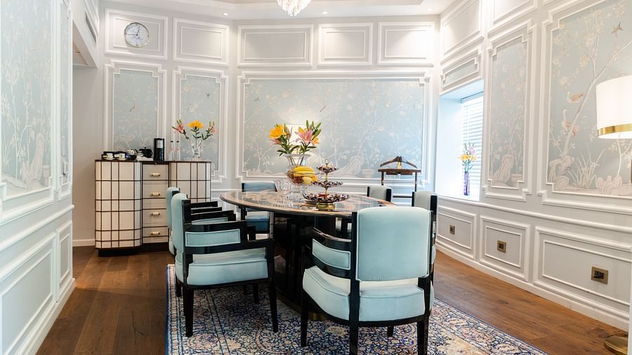 A dining table with blue cushioned chairs on either side in the living area of our Diplomatic suite in New Delhi at the Claridges
