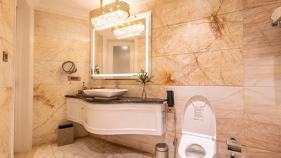 image of the bathroom with a sink and a square shaped mirror with a commode - The Claridges New Delhi