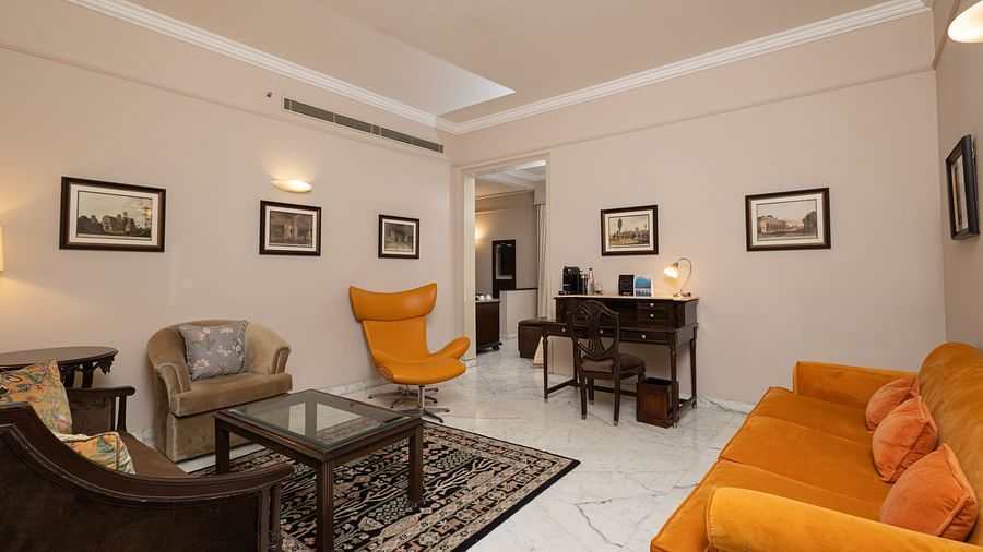 image of the living area with white marble flooring and bright yellow couch at the heritage parlour suite - The Claridges New Delhi