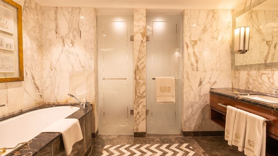 Interior of the Cabana Room bathroom featuring the bathtub, sink, and two glass doors at the front - The Claridges New Delhi